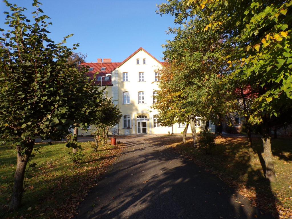 a large white building with trees in front of it at Apartament Parkowy in Kętrzyn