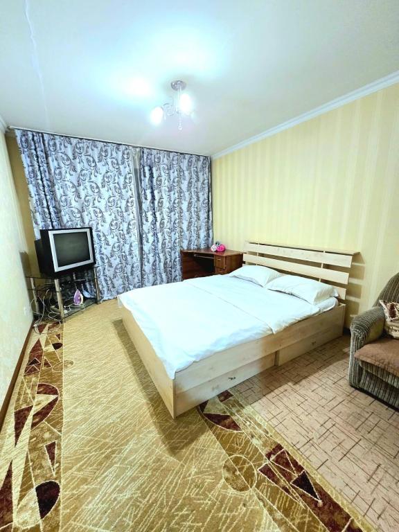 a bedroom with a bed and a television and a couch at Аэропорт Астана 5 минут 1 in Astana