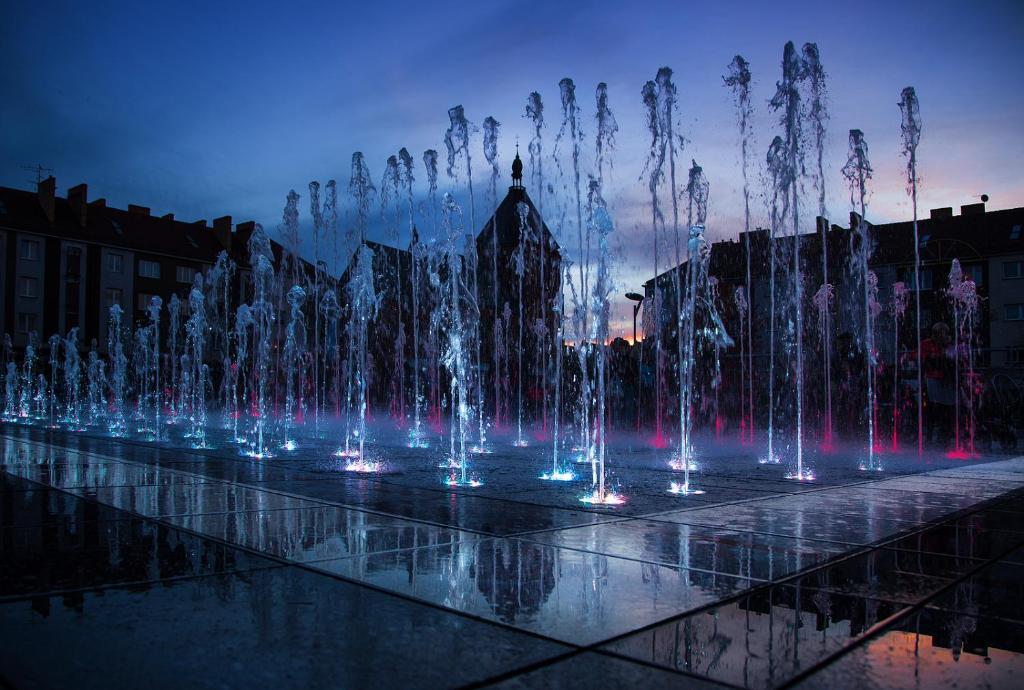 a water fountain in a city at night at 100-SIO Apartamenty in Koszalin