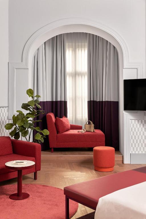 a living room with a red couch and a tv at Falkensteiner Boutique Hotel Prague in Prague