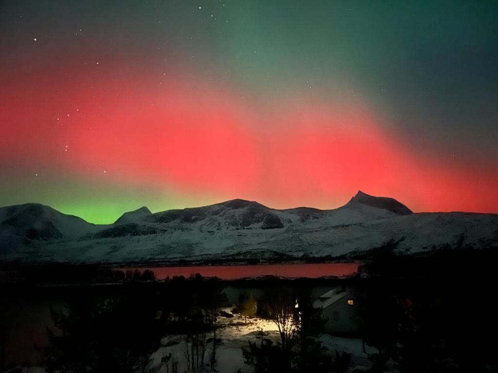 an aurora in the sky over a snow covered mountain at Efjord and Stetind Resort - Cabin Kulhorn in Ballangen