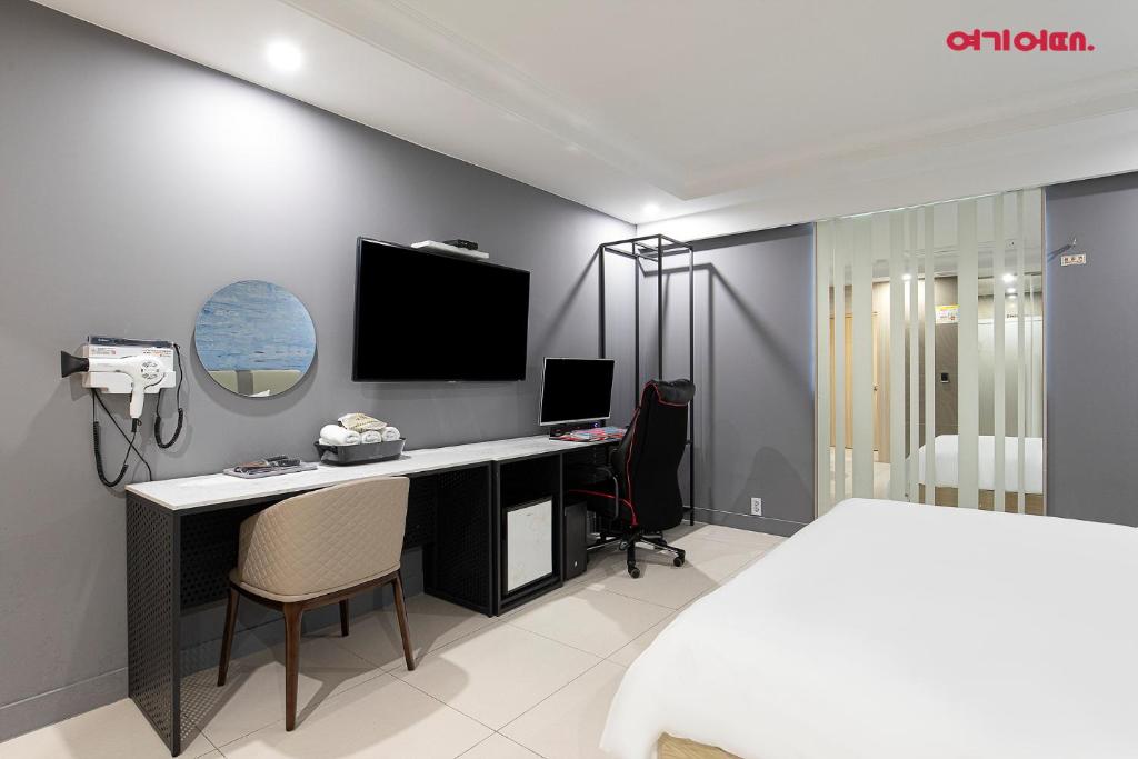 a bedroom with a desk and a tv on a wall at INCHEON AIRPORT HOTEL THE ONe in Incheon