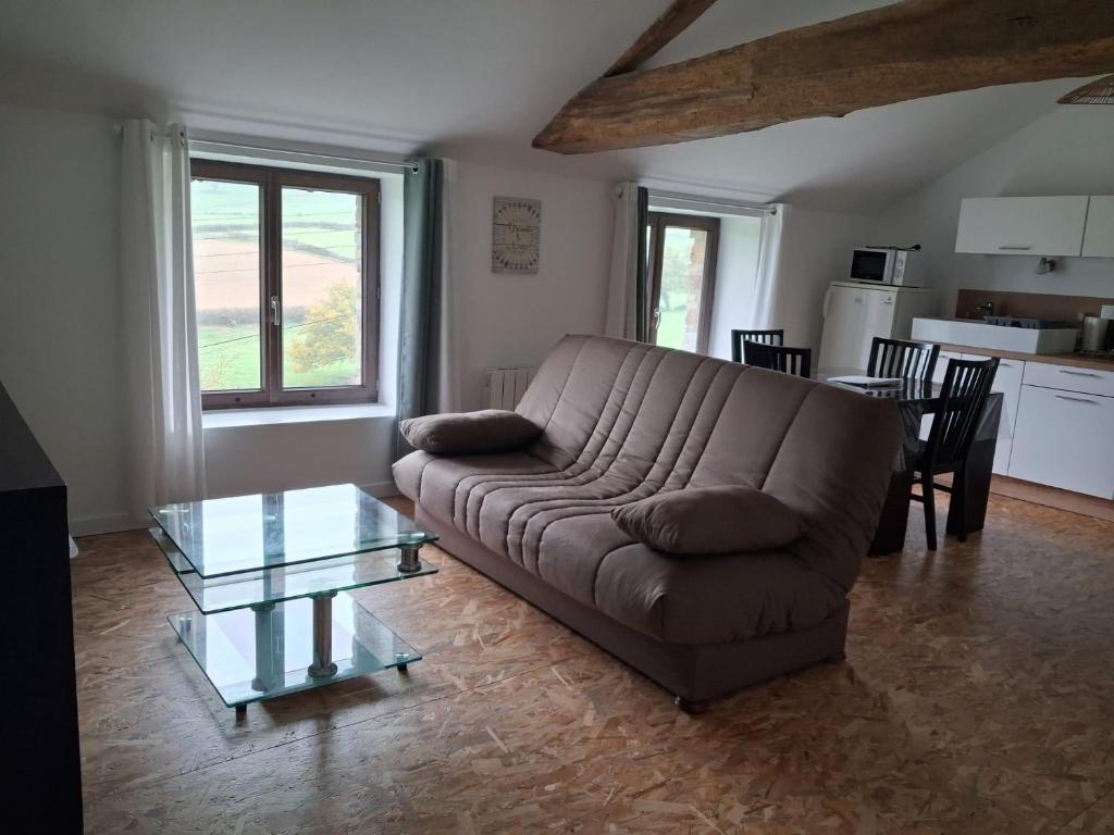 a living room with a couch and a glass table at Les Gîtes de Sophinette in Dompierre-les-Ormes