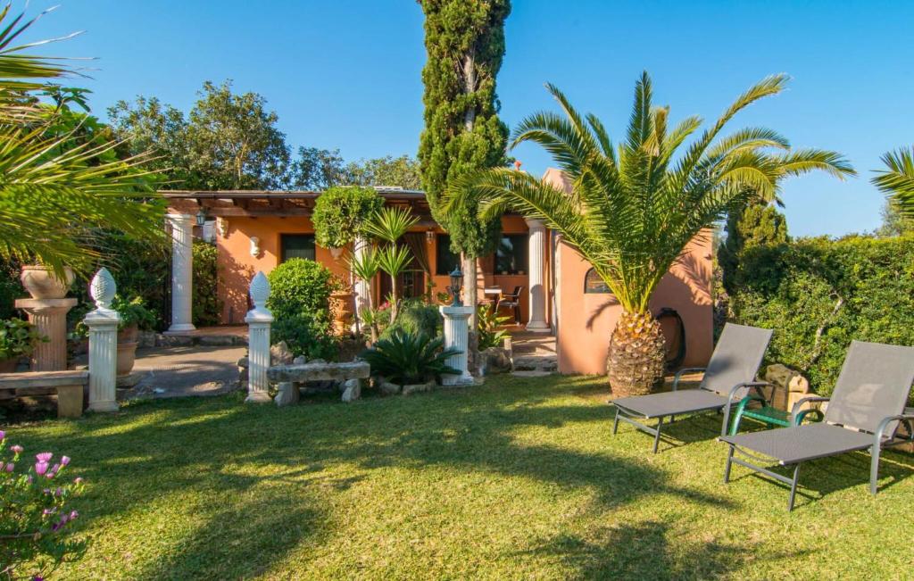 a house with a yard with two chairs and palm trees at Silencio in Cala Ratjada