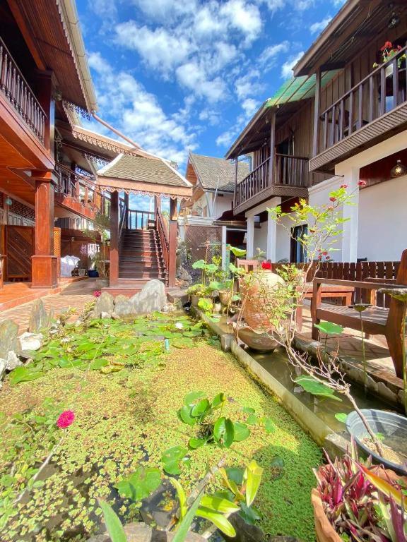a house with a pond in front of a building at Villa Chaluenxay Boutique Hotel 2 in Luang Prabang