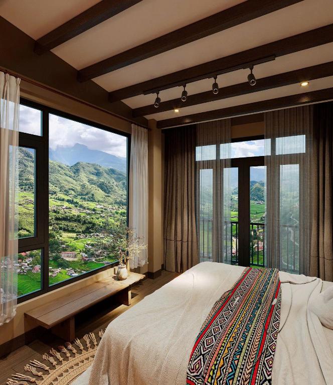 a bedroom with a large bed and large windows at Voi Meo Vac Hostel & Breakfast in Mèo Vạc