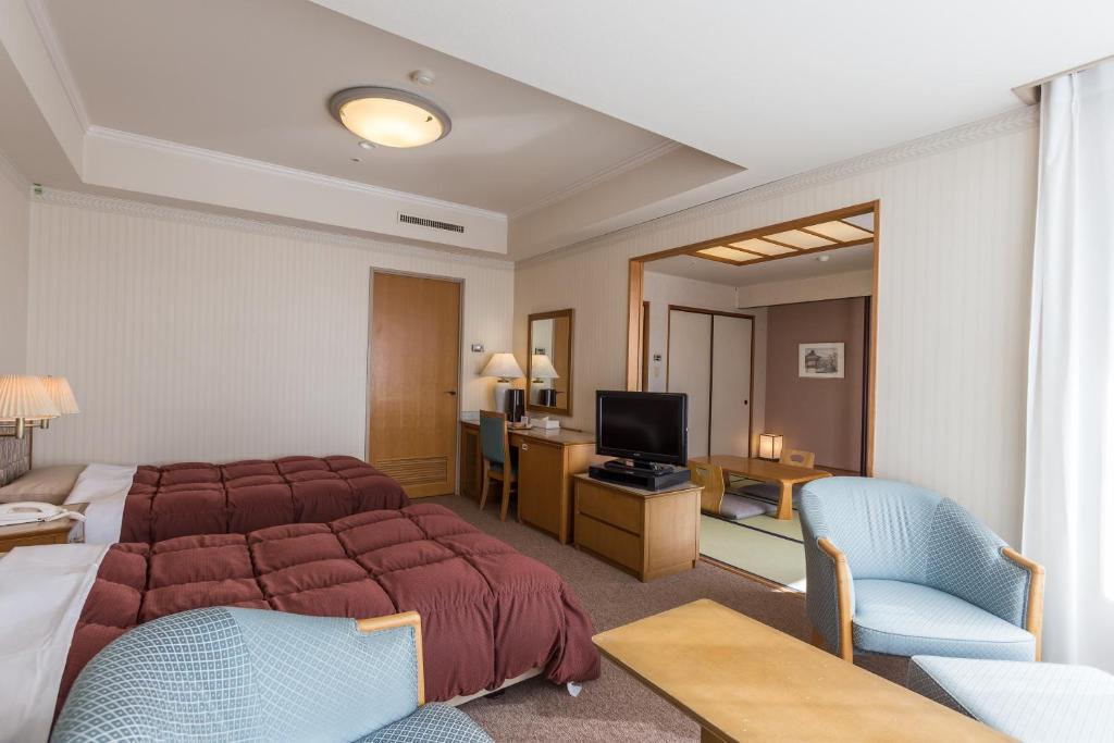 a hotel room with a bed and a television at Kusatsu Onsen Hotel Village in Kusatsu