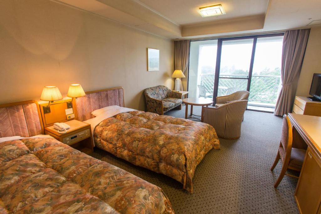 a hotel room with two beds and a living room at Kusatsu Onsen Hotel Village in Kusatsu