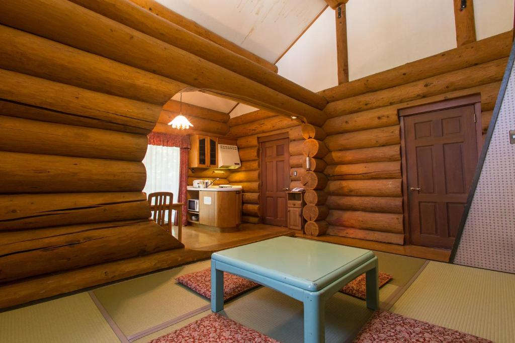 a room with a table in a log cabin at Kusatsu Onsen Hotel Village in Kusatsu