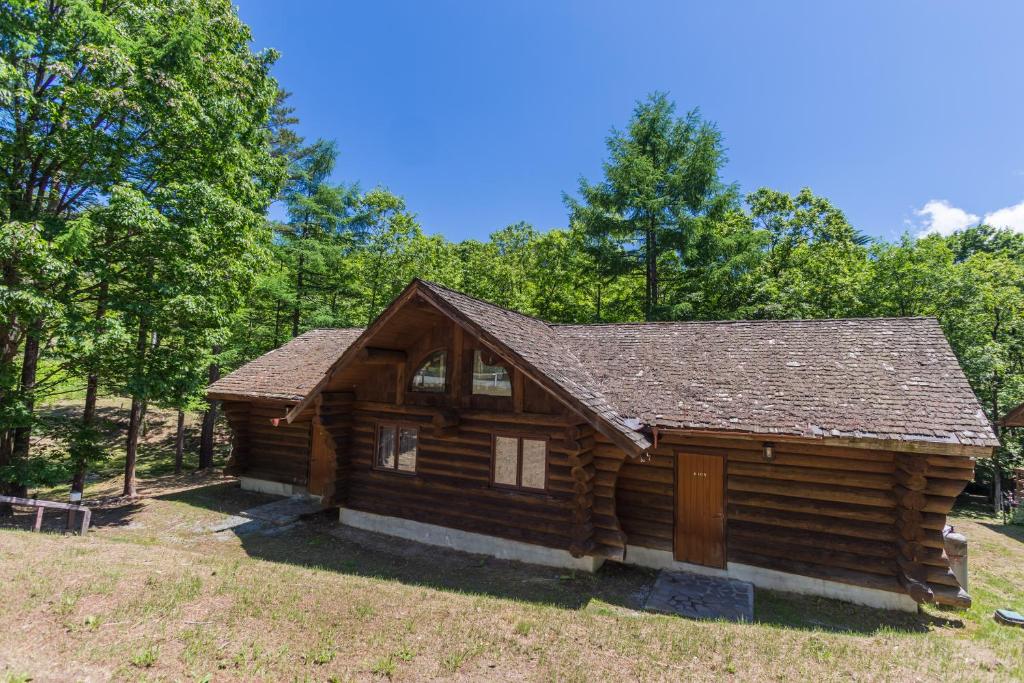 a log cabin with trees in the background at Kusatsu Onsen Hotel Village in Kusatsu