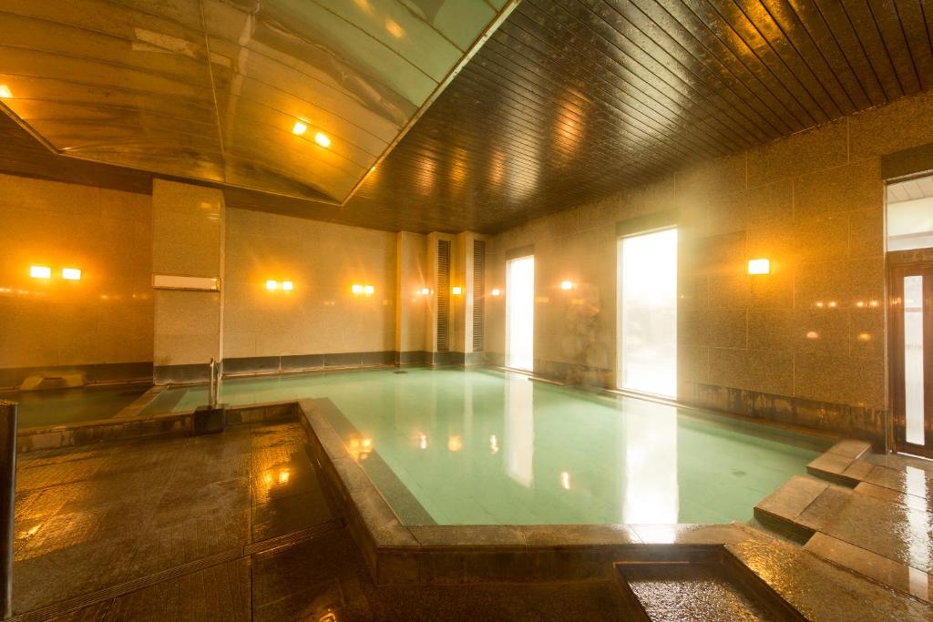 a swimming pool in a building with a pool at Kusatsu Onsen Hotel Village in Kusatsu