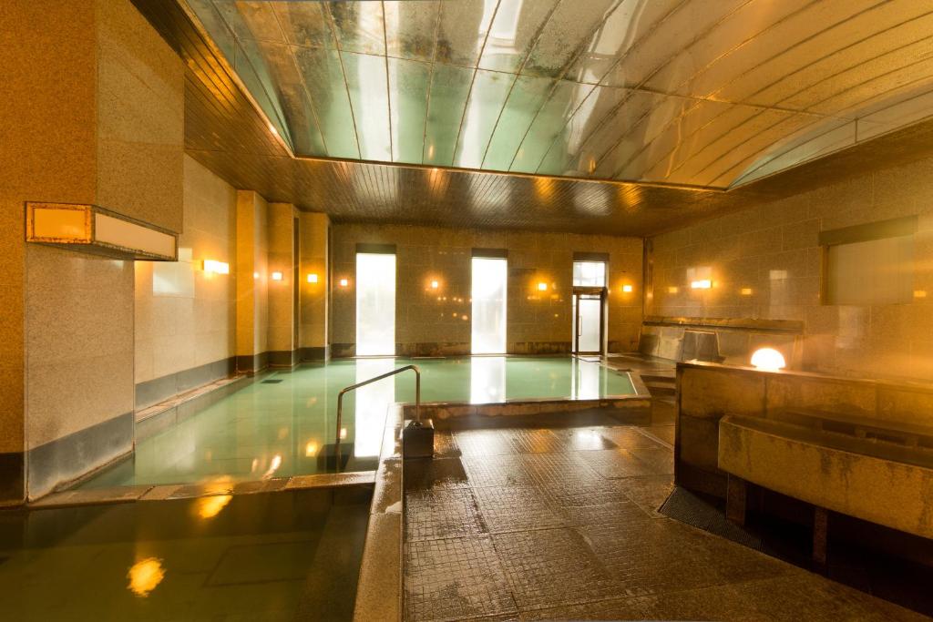 a swimming pool in a large building with a pool at Kusatsu Onsen Hotel Village in Kusatsu