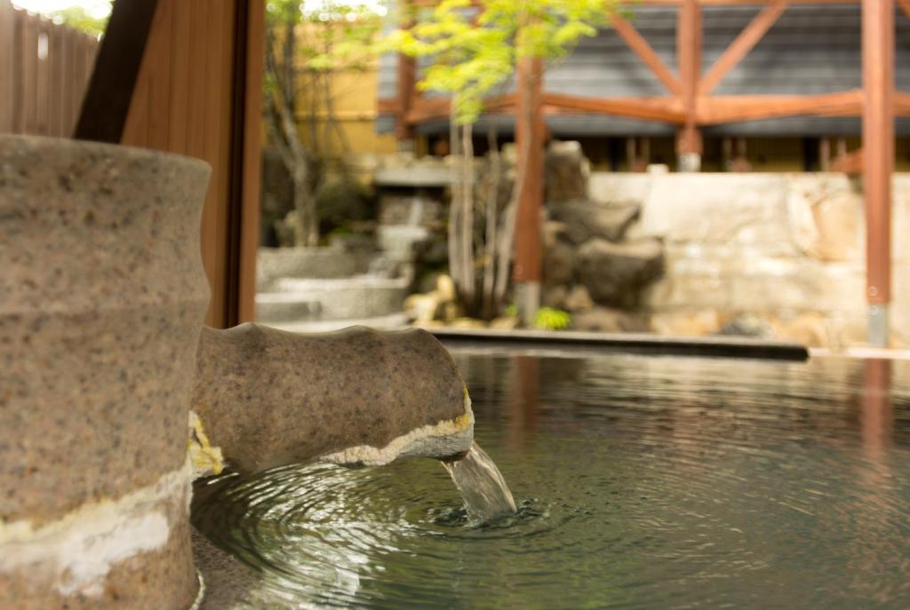 a bird drinking water from a fountain in a pond at Kusatsu Onsen Hotel Village in Kusatsu