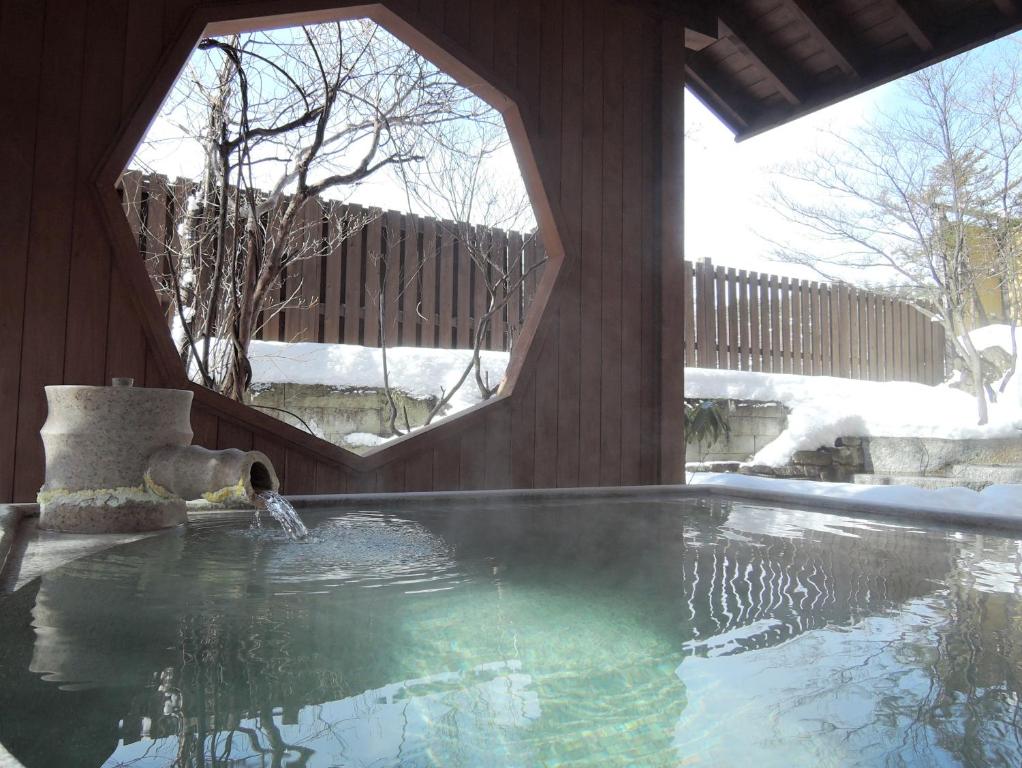 a swimming pool with a water fountain in a house at Kusatsu Onsen Hotel Village in Kusatsu