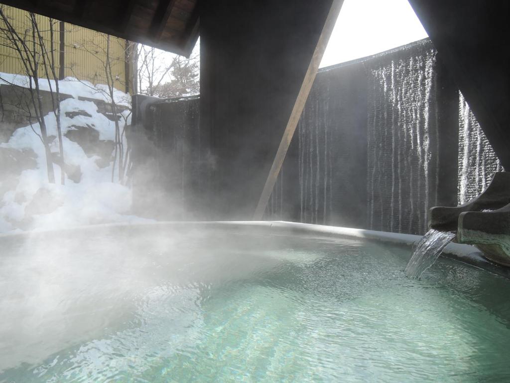 a hot tub with a shower with steam coming out at Kusatsu Onsen Hotel Village in Kusatsu
