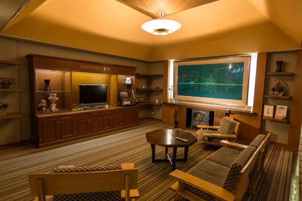 a living room with a television and a table and chairs at Kusatsu Onsen Hotel Village in Kusatsu