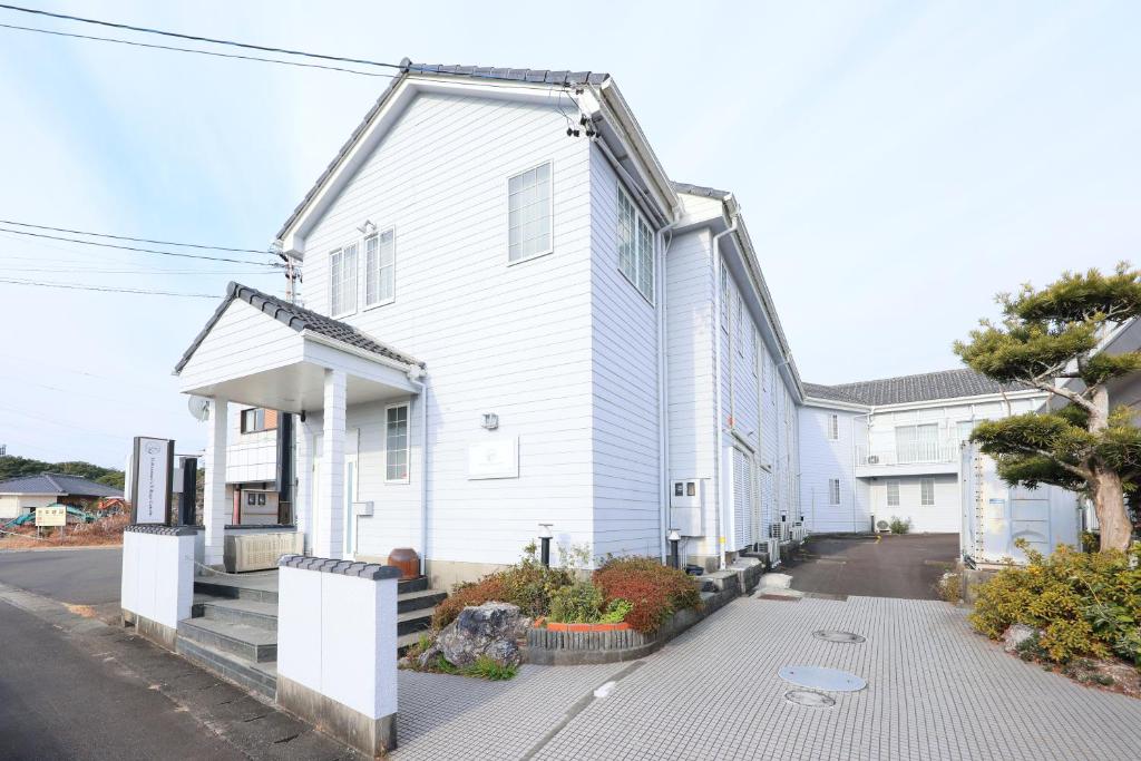 a white house with a porch and a driveway at GATE80伊勢志摩 無人宿 完全セルフ 予約メッセージ欄確認要す スマートロック 暗証番号チェックイン 素泊まり専門 アメニティ持参で格安滞在 セコム24h監視 駐車場7台 in Shima