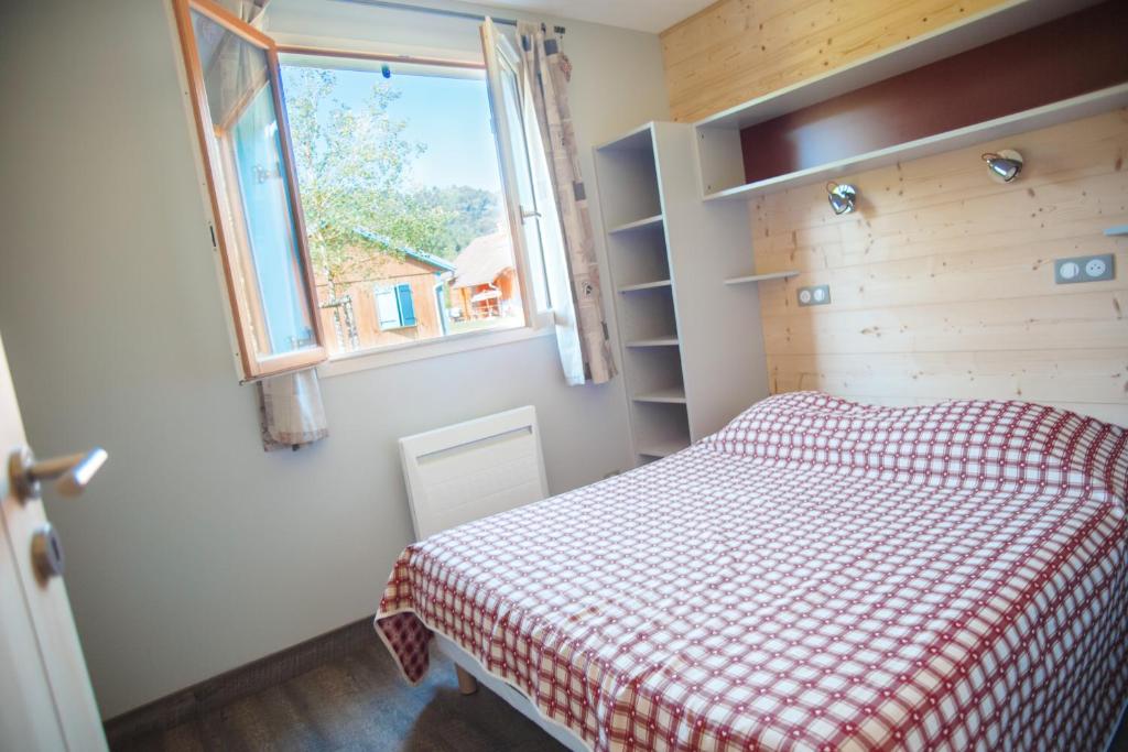 una piccola camera con letto e finestra di Camping Base de Loisirs du Lac de la Moselotte a Saulxures-sur-Moselotte