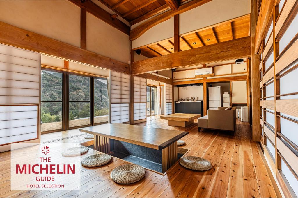 a large living room with a wooden table and windows at B&B ITADAKI in Shizuoka