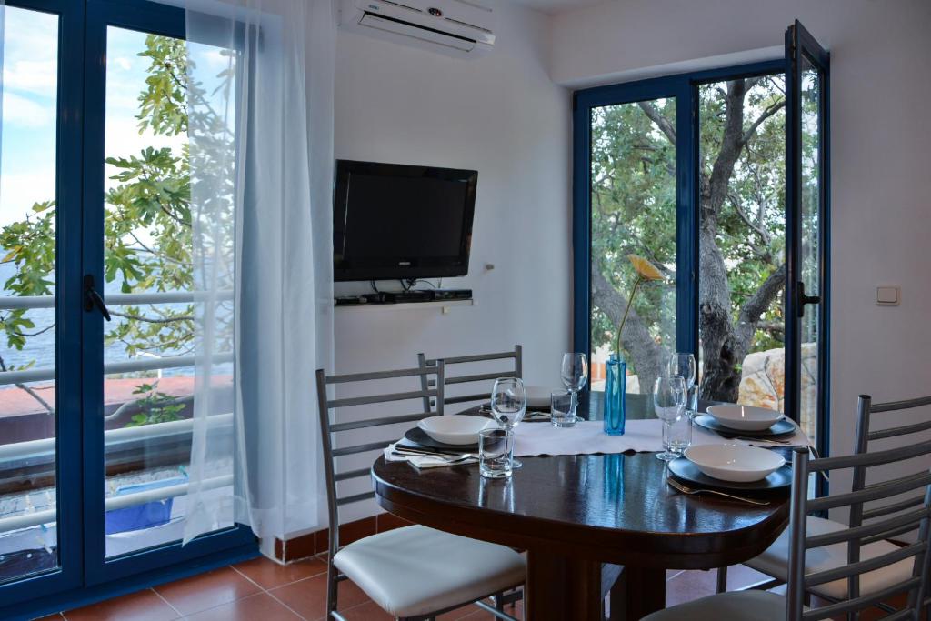 a dining room with a table and chairs and a tv at Apartments Miki in Donja Klada