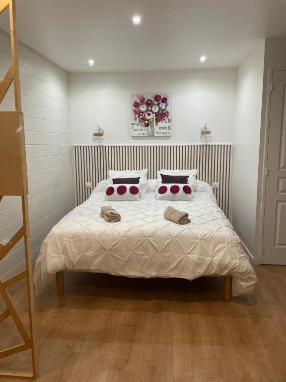 a bedroom with a bed with white sheets and red pillows at La Parenthèse de Victoire in Aigues-Mortes