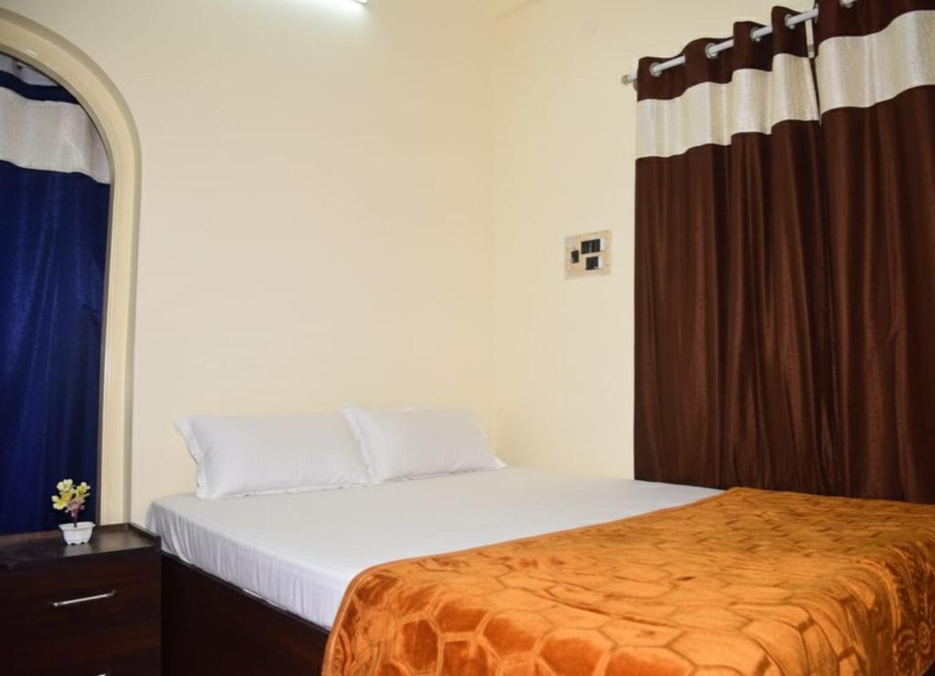 a bedroom with a bed with a orange blanket at Joyful Homestay in Mysore
