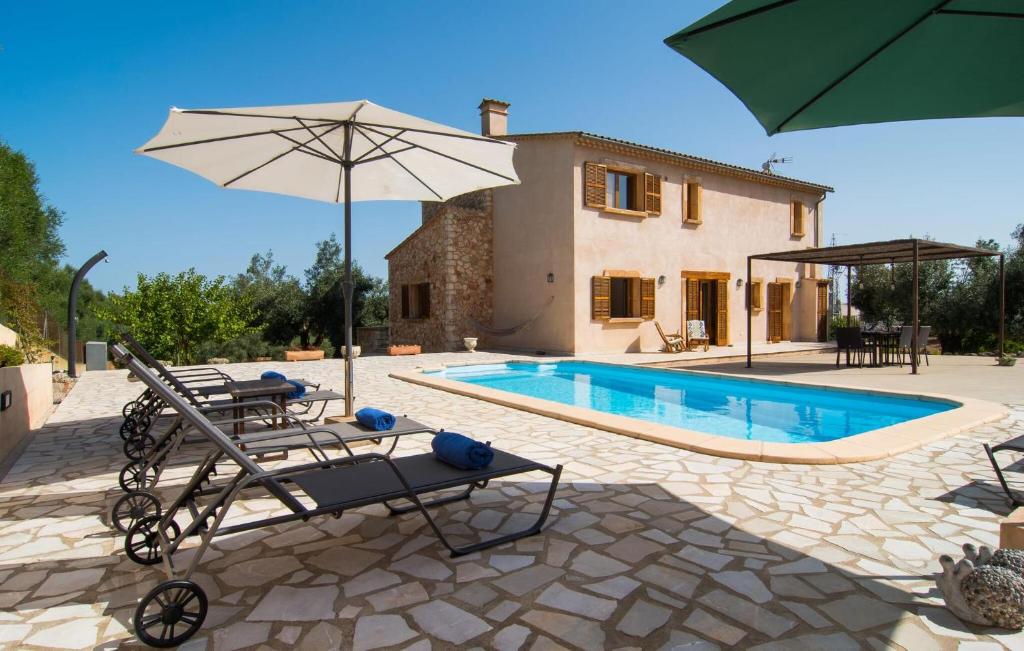 a pool with chairs and an umbrella next to a house at Sa Finqueta in Manacor