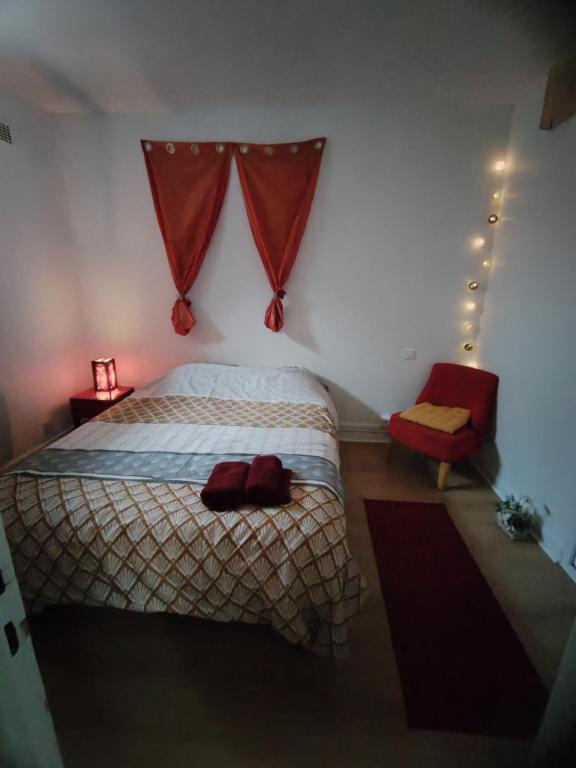 a bedroom with a bed and a red chair at appartement dans maison de village in Pinet