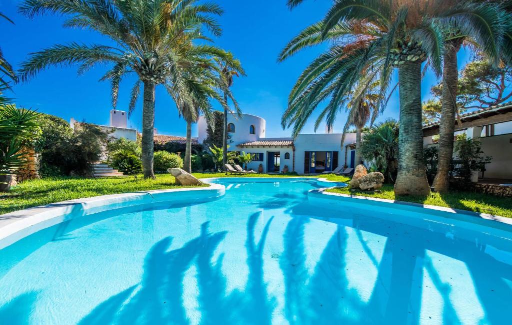 a pool with palm trees in front of a house at Can Roca De Cala D'or in Cala d´Or