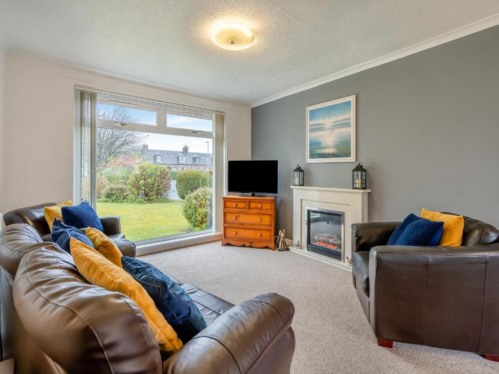 a living room with a leather couch and a television at The Mulberry in Lamlash