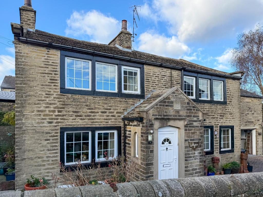 a brick house with a white door at Wellhead Cottage in Haworth
