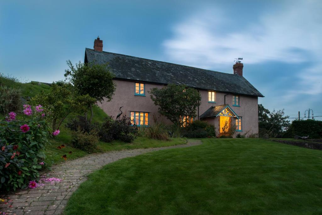 una casa con sus luces encendidas en un patio en The Old Dairy at Bishops Barton, en Wellington