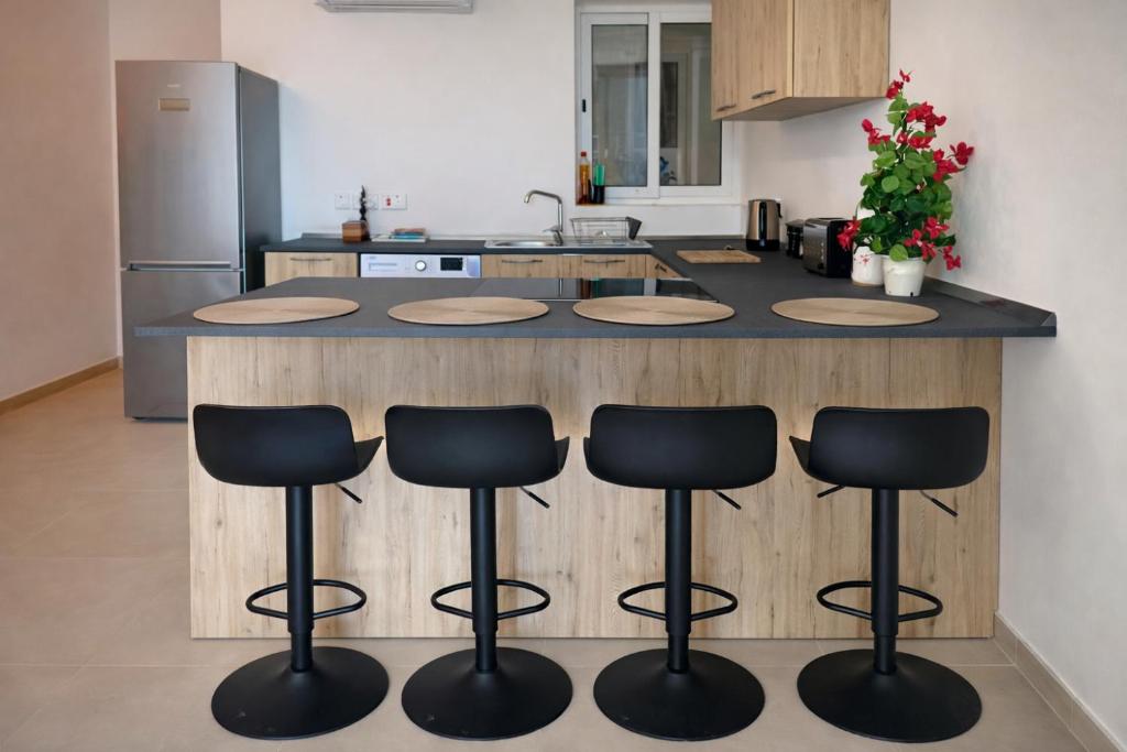 a kitchen with a counter with four bar stools at Comfortable ! Stylish ! Fully Air Conditioned ! in Sannat