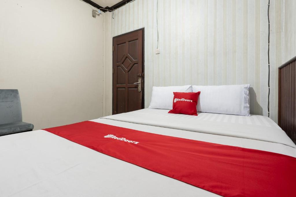 a bed with a red and white blanket on it at RedDoorz Syariah near Pasar Pagi Samarinda in Samarinda