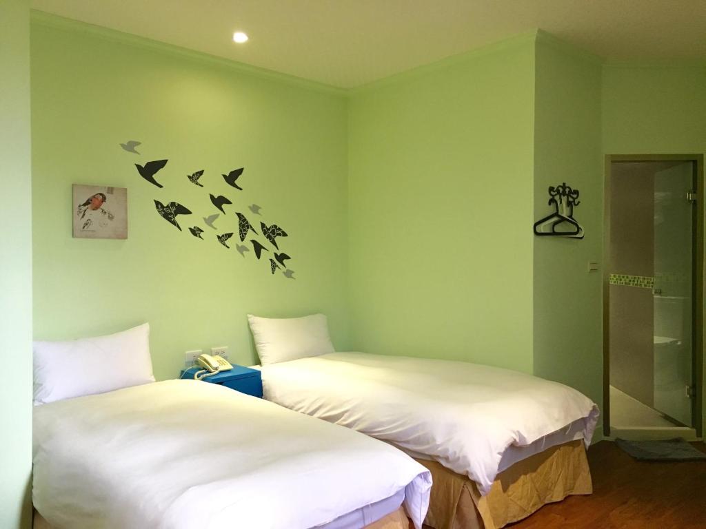 twee bedden in een kamer met vogels aan de muur bij Wan Tai Hotel in Chiayi City