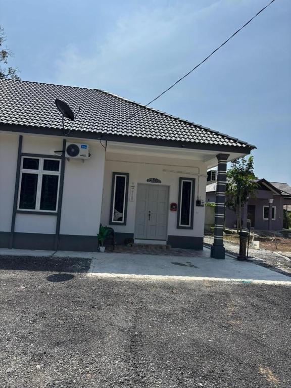 a small white house with a driveway at Airisafiq Homestay in Kampong Sungai Rambai