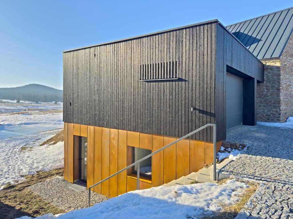 a house with a wooden facade in the snow at Apartmán Ore&Moor in Boží Dar