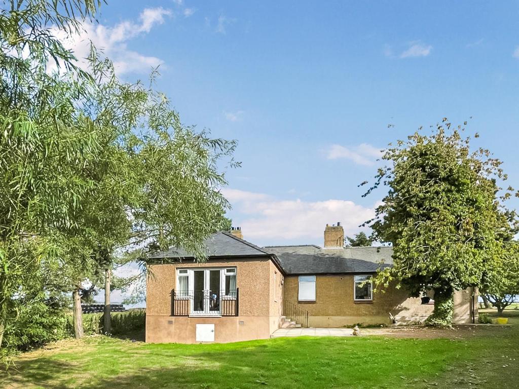 a brick house with a balcony on a yard at Holly Croft in Drem