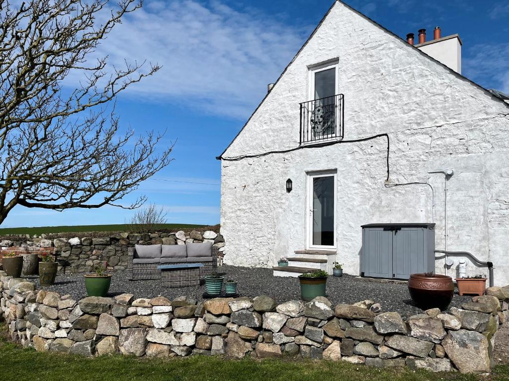 a white building with a stone wall in front of it at The Cheese Loft in Drummore