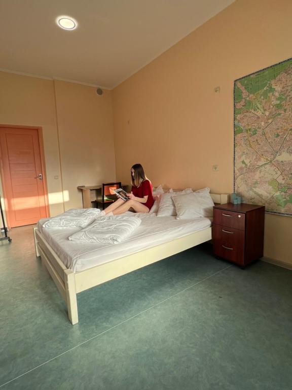 a woman sitting on a bed reading a book at Demeevsky Hostel in Kyiv