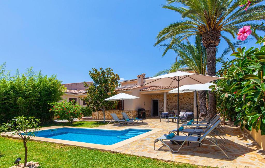 a villa with a swimming pool and a palm tree at Mirte in Sa Coma