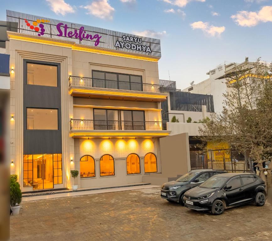 two cars parked in a parking lot in front of a building at Sterling Saryu Ayodhya in Ayodhya
