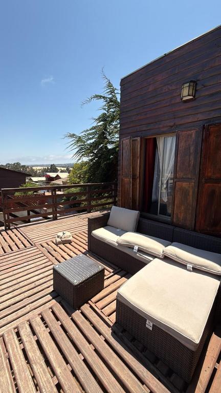 a wooden deck with a couch and tables on it at Cabaña Las Cruces in Las Cruces