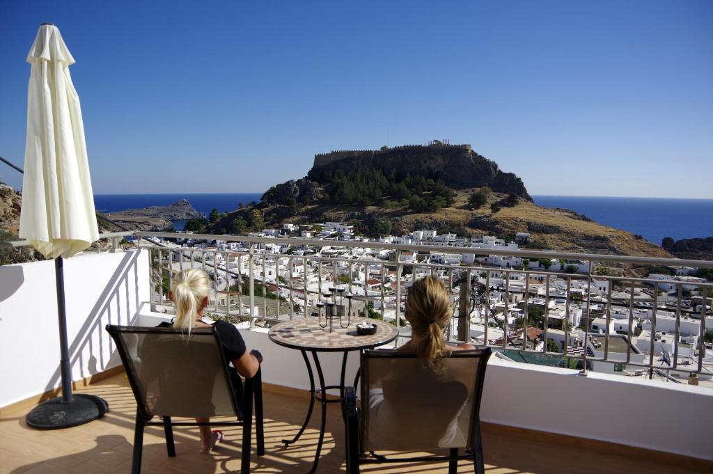 リンドスにあるLindos Anatoli Luxury Villaの市街を見渡すバルコニーのテーブルに座った女性2名