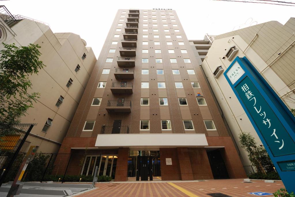 a tall building with a sign in front of it at Sotetsu Fresa Inn Hamamatsucho-Daimon in Tokyo