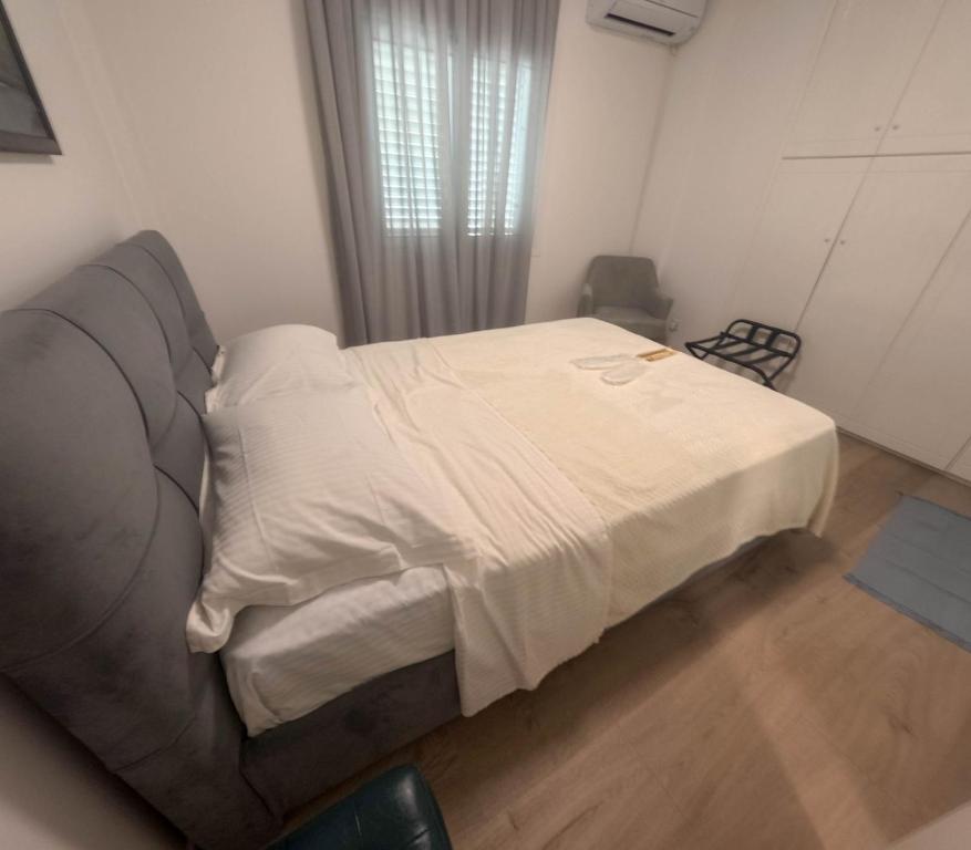 a bedroom with a bed with white sheets and a couch at Athalassas corner in Strovolos