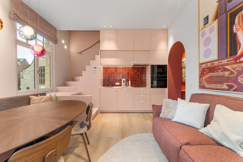 a kitchen and living room with a couch and a table at stijlvol appt met adembenemend uitzicht op het centrum van Ieper in Ieper