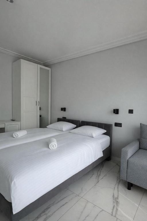 a bedroom with a large white bed and a chair at Apartamenty Odrodzenia 11 in Szczytno