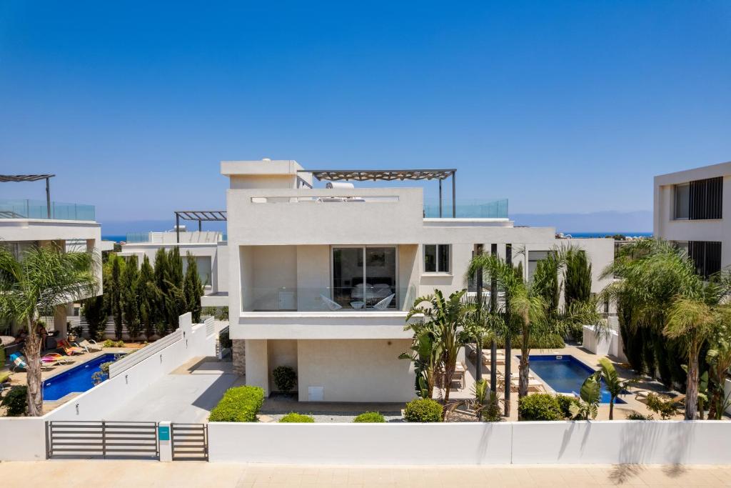 a white house with a swimming pool and palm trees at Levanda Hills Haven in Protaras in Paralimni