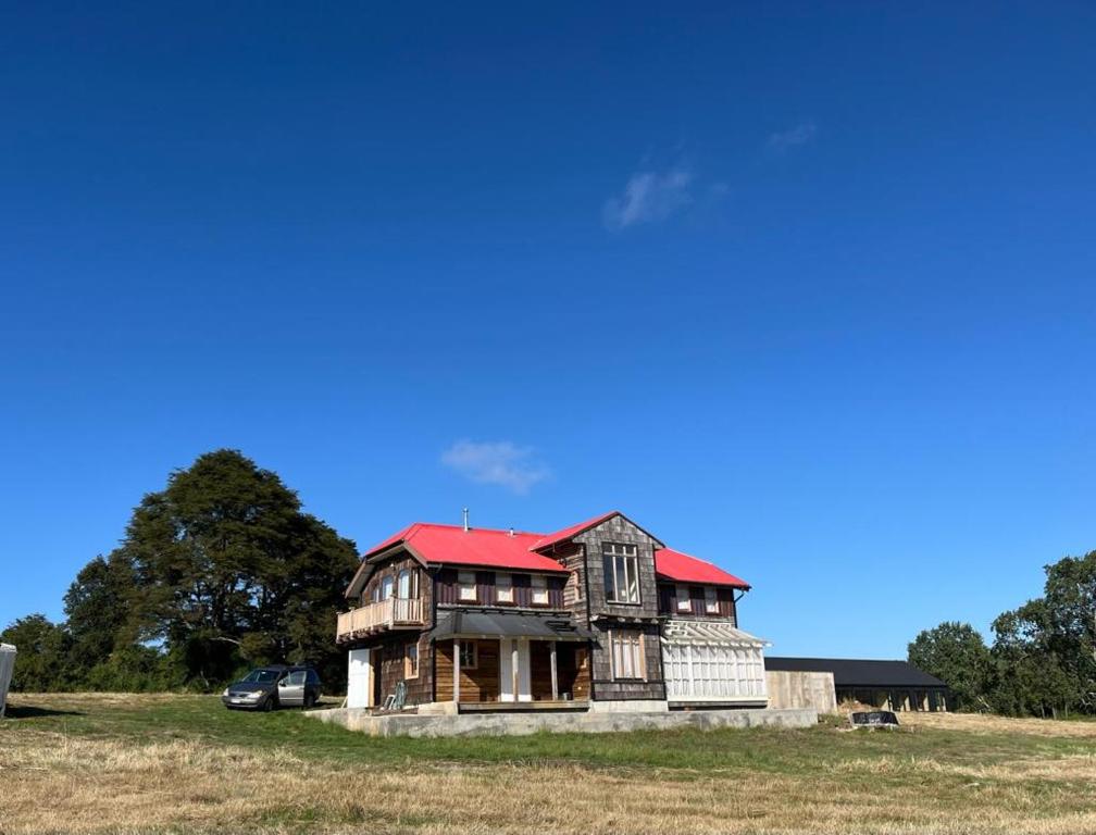 an old house with a red roof in a field at Refugio del Sur, Escapada in Llanquihue
